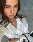 Woman wearing a white shirt with a gold letter necklace